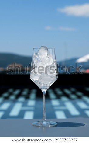 Drinking glass filled with ice cubes near swimming pool