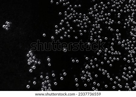 Many small and large air bubbles underwater. The concept of the microworld, the distribution of micro-objects and neural connections within artificial intelligence. Black background. Photo. Macro Royalty-Free Stock Photo #2337736559