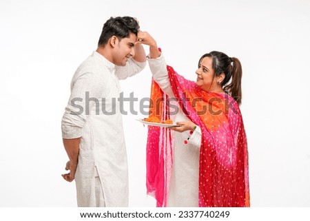 Indian brother and sister celebrating Raksha Bandhan or Rakhi festival. sister getting tika on brother head. Royalty-Free Stock Photo #2337740249