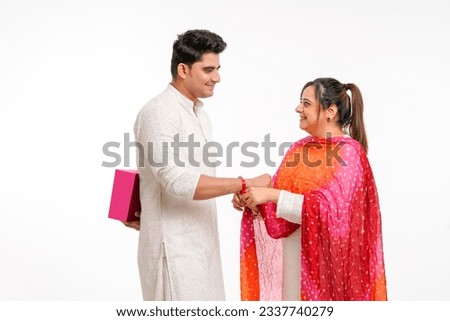 Indian good looking young brother and sister celebrating Raksha Bandhan or Rakhi festival. Royalty-Free Stock Photo #2337740279