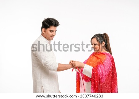 Indian brother and sister celebrating Raksha Bandhan festival. sister tie rakhi or wristband on brother hand. Royalty-Free Stock Photo #2337740283