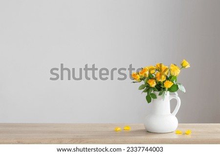 yellow roses in white jug on wooden shelf Royalty-Free Stock Photo #2337744003