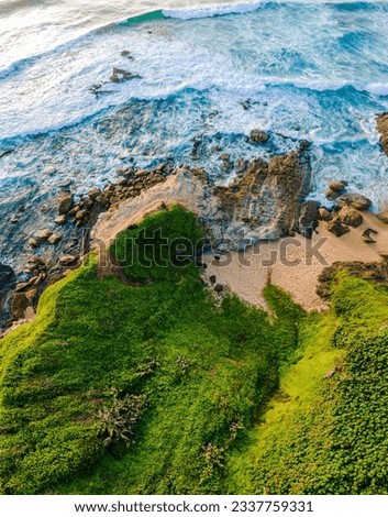 Spring-Morning Ocean and Green Hill Overhead Aerial Drone Image Of Blue Waves Crashing Onto The Rocky Shore. Picture Shot In Ballito, South Africa.