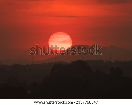 the sun sets in orange hues covered by the trees and mountain. The photo was taken by Willem Tasiam, a marathon climber