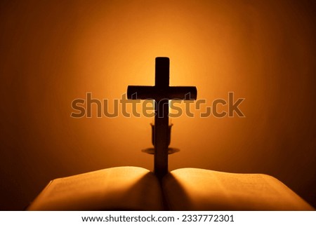 Light candle with holy bible and cross or crucifix on old wooden background in church.Candlelight and open book on vintage wood table christianity study and reading in home.Concept of christ religion Royalty-Free Stock Photo #2337772301