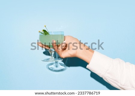 Women hand holding glass with margarita cocktail on light blue pop art background. Copy space for ad. Concept of party, relax, alcohol. Royalty-Free Stock Photo #2337786719