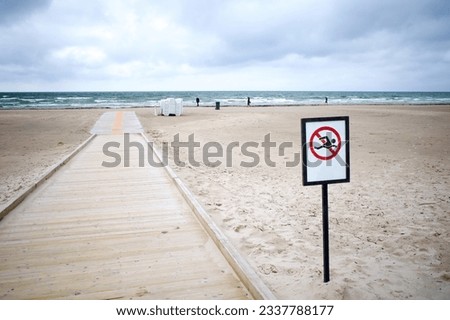 Sign prohibiting swimming in the Baltic Sea. Waste water leak in Liepaja, Latvia. Selective focus.