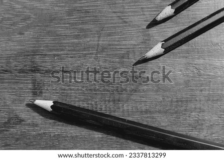 Close-up shot of pencils and texture, wooden table, black and white photo