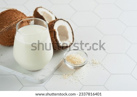 Glass of coconut milk and coconut close up on a white background with space for text. Coconut vegan milk non dairy or Dairy free milk concept. Healthy vegan food.  Royalty-Free Stock Photo #2337816401