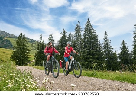 two senior girlfriends having fun during a cycling tour in the Allgau Alps near Oberstaufen, Bavaria, Germany Royalty-Free Stock Photo #2337825701