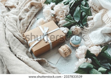 Gift box with bow, white peonies and sweet macaroons, holiday concept.