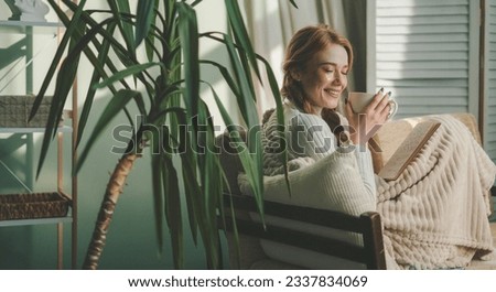 Beautiful caucasian woman sipping morning coffee while concentrating reading a book in her living room. Lady studying textbook. Person spending time resting in Royalty-Free Stock Photo #2337834069