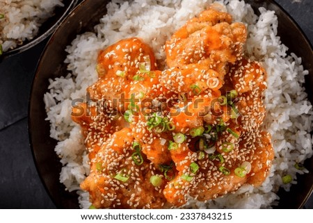 Savory Delights: Close-Up of Deep-Fried Orange Chicken Served on a Bed of Steamed White Rice, Captured in 4K Resolution