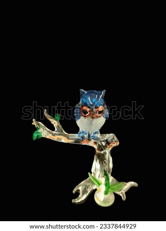 Funny colorful owl figurine isolated on black background.