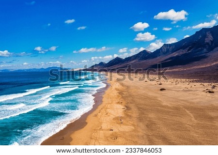 Amazing Cofete beach with endless horizon. Volcanic hills in the background and Atlantic Ocean. Cofete beach, Fuerteventura, Canary Islands, Spain. Playa de Cofete, Fuerteventura, Canary Islands. Royalty-Free Stock Photo #2337846053