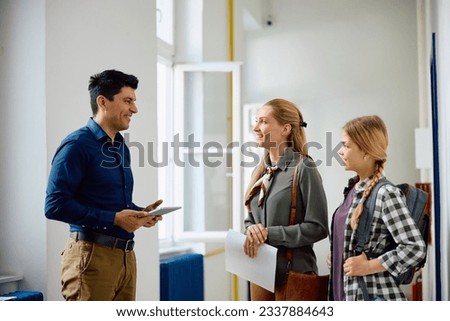 Happy principal talking to mother and daughter about enrolling in high school. Royalty-Free Stock Photo #2337884643