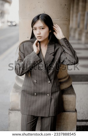 A beautiful young Asian girl is walking around Paris in stylish clothes.