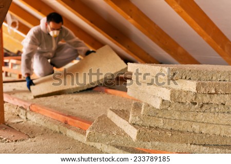 Man installing thermal insulation layer under the roof - using mineral wool panels Royalty-Free Stock Photo #233789185