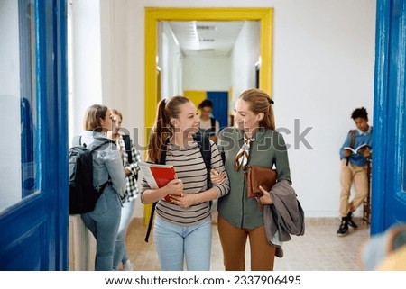 Happy mother and her teenage daughter walking through high school hallway.