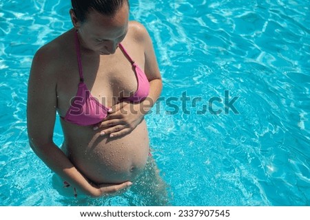 Pregnant woman relaxing in the swimming pool. About 30 years old.