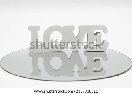 white wooden letters with the word love reflected in a round mir
