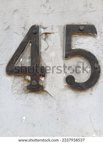 Vintage photo of number forty five on cracked wall, made of old bronze plate. 