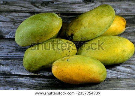Pile of Egyptian fresh mango fruit with tropical delicacy, mangoes are nutritionally rich fruit with distinctive flavor, smell, taste, selective focus of Taimoor Mango fruit isolated on wood