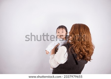 Beautiful photo of loving mom with baby on light photo studio background. Family and baby concept.