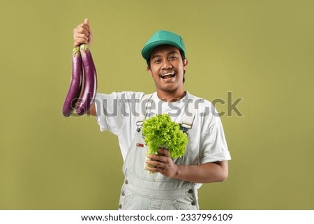 Photo of asian young man holding raw vegetables over green background.