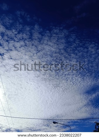 Power cables and streetlights  with a fluffy white cloud background