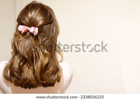 Young blonde woman with hair styled half-back, secured with a bow clip. Valentines day hairstyle. Sweet hairstyle. Healthy, glossy hair. Cool vintage filter.  Royalty-Free Stock Photo #2338036233