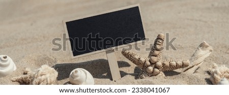 Empty blackboard frame board with copy space for your text or design displays on sandy beach. Starfish and shells decoration. Summer vacation and holiday business travel concept. Template Mock up for