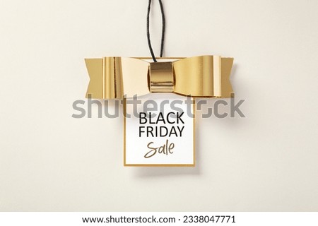 Black friday sale tag with gold bow on beige background Royalty-Free Stock Photo #2338047771
