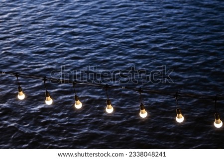 Light bulbs lined up by the sea in the evening