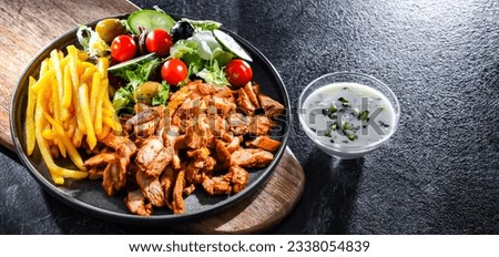 Kebab served with french fries, vegetable salad and tzatziki Royalty-Free Stock Photo #2338054839