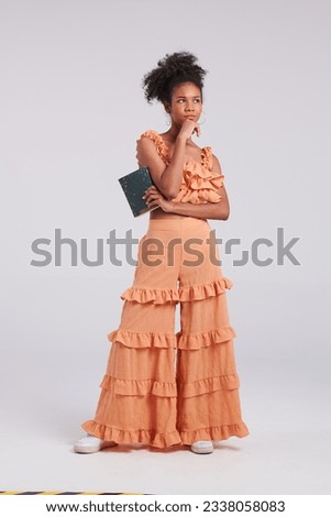 A seamless blend of fashion and literature defines the studio moment of a girl in an orange shirt, creating a mesmerizing stock photo.