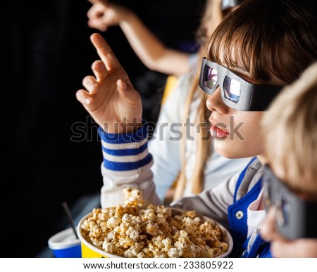 Girl pointing while watching 3D movie with siblings at cinema theater