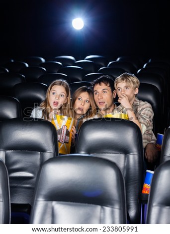 Amazed family of four watching movie in cinema theater