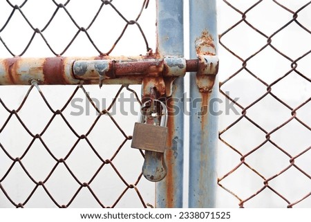 Old Rusty Security Slide Bolt Lock with Pad Lock Wire Mesh Door Royalty-Free Stock Photo #2338071525