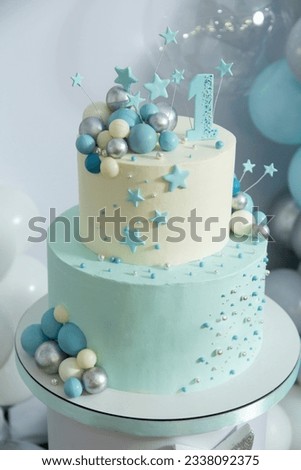 two tiered blue first birthday cake decorated with balloons and stars
