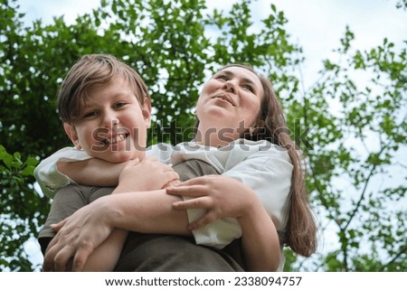 Authentic image from a garden photoshoot, capturing a mother and her pre-teen son in a genuine laugh, portraying the beauty of natural photography Royalty-Free Stock Photo #2338094757