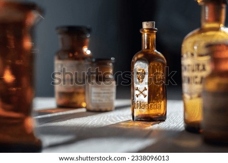 Poison bottle with skull and bones stands among pharmaceutical bottles. Danger sign, symbol of death. Concept background on poison poisoning, pharmaceutical, chemistry, medical, old science topic.  Royalty-Free Stock Photo #2338096013