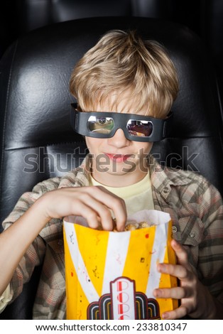 Portrait of boy eating popcorn while watching 3D movie in cinema theater