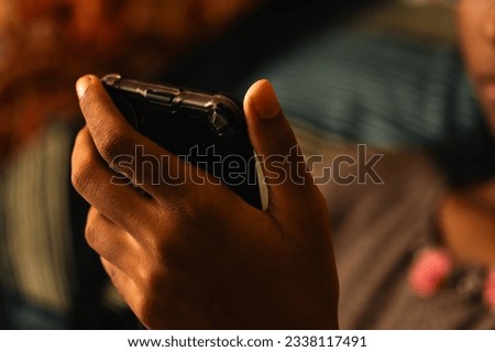 Cell phone used by Indian ethnic girl child - low light edit - selective focus