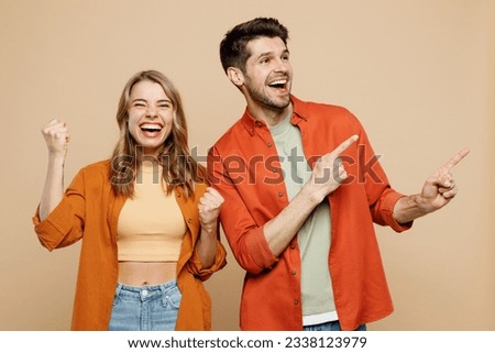 Young couple two friends family man woman wear casual clothes point index finger aside on area mock up do winner gesture together isolated on pastel plain light beige color background studio portrait Royalty-Free Stock Photo #2338123979