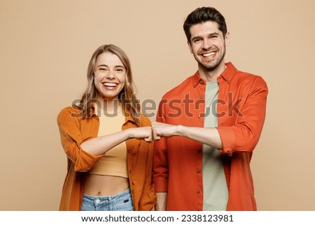 Young smiling happy buddies fun couple two friends family man woman wear casual clothes looking camera giving fist bumo together isolated on pastel plain light beige color background studio portrait