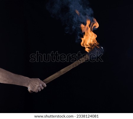 burning wooden torch in hand isolated on black background Royalty-Free Stock Photo #2338124081
