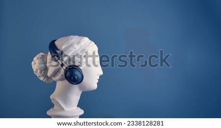 An elegant profile of the plaster head of a beautiful Aphrodite in stylish blue headphones on a harmonious background. Banner, copy space view. The concept of listening to music, audiobooks, podcasts.