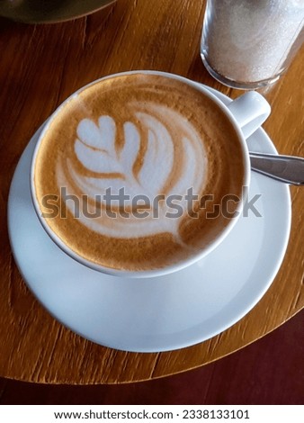 Cup of coffee taken photo candidly with milk foam forming a shape of a flower