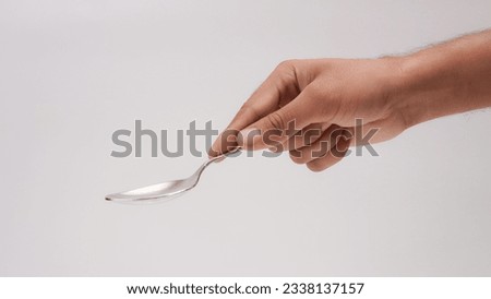 Male Hand Holding A Silver Stainless Spoon Closeup Photo Isolated On Grey Background
